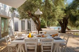 a white table and chairs on a patio with trees at Villa Mavrades in Sivota