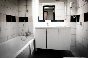 a bathroom with a sink and a tub and a mirror at Havila Hotel Geiranger in Geiranger
