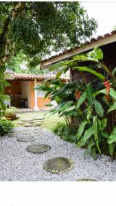 a garden with rocks and a house and a bush at Boiçucanga litoral Norte in Boicucanga