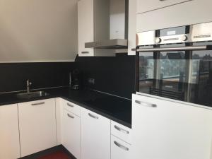 a kitchen with white cabinets and a black counter top at Penthouse Belle Vue in Bergen aan Zee