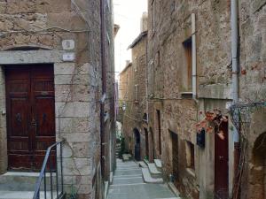 un callejón con escaleras y una puerta de madera en La grotta del ghetto, en Pitigliano