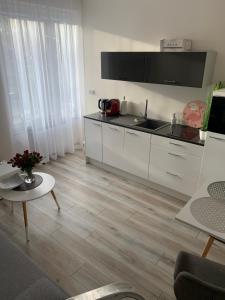 Apartament Walczaka 25 MIEJSCE PARKINGOWE في جورزو فيلكوبولسكي: غرفة معيشة مع مطبخ مع دواليب بيضاء