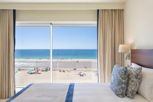 Residence Sol e Mar في ساليما: غرفة نوم بسرير وإطلالة على الشاطئ