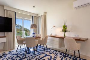 een woonkamer met een tafel en stoelen en een televisie bij Residence Sol e Mar in Salema