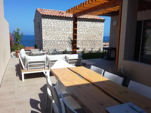 Una mesa y sillas de madera en un patio con vista al mar. en Domaine A Mortella T2, en Saint-Florent