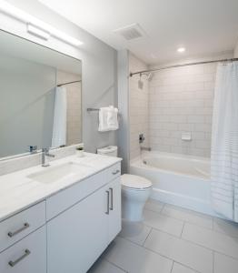 un bagno bianco con vasca, WC e lavandino di Bluebird Suites Near Chevy Chase a Bethesda Altre 41 foto