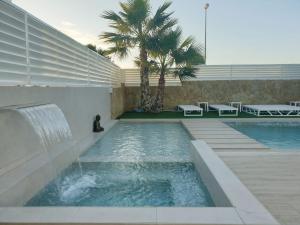 una piscina con una fuente y una palmera en VILLA AMANI, en San Fulgencio