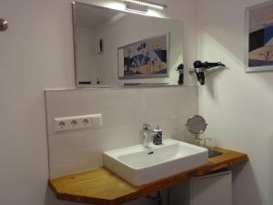 een badkamer met een witte wastafel en een spiegel bij Ferienwohnung Eulenloch in Nördlingen