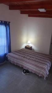 a bedroom with a bed with a lamp on a table at Casa en Mayú Sumaj a metros del Río. in San Antonio de Arredondo