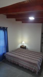 een slaapkamer met een bed en een lamp op een tafel bij Casa en Mayú Sumaj a metros del Río. in San Antonio de Arredondo