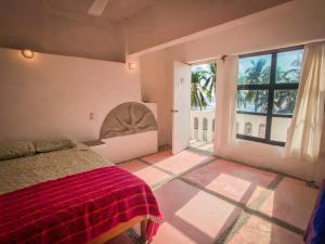 a bedroom with a bed and a large window at La Coral Beach House in Puerto Escondido