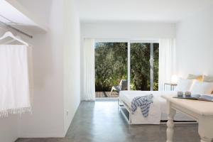 a white bedroom with a bed and a table and a window at Villa Mavrades in Sivota