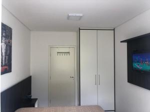 1 dormitorio con cama y armario blanco en Loft Campos do Jordão - SP, en Campos do Jordão