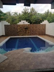 a swimming pool in a backyard with a brick wall at Brisas del Magdalena in La Dorada