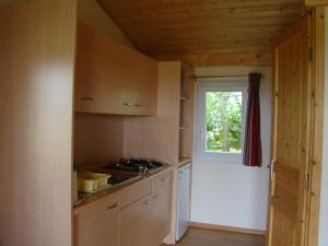 una cocina con armarios de madera y una ventana en CAMPING LES GRAVES, en Saint-Pierre-Lafeuille