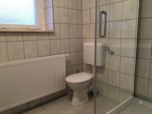 een badkamer met een toilet en een glazen douche bij FEWO Appartement 5 in Minden