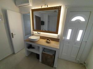 a bathroom with a sink and a mirror and a door at Maya Apartments in Dexamenes