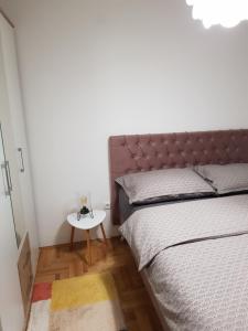 a bedroom with a bed and a side table at Sunrise apartman in Bijeljina