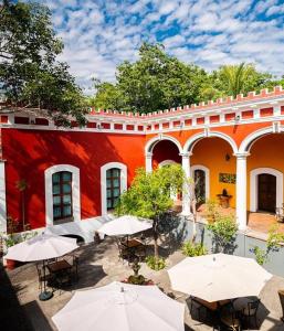 a courtyard with tables and umbrellas in front of a building at Hotel Boutique Hacienda del Gobernador in Colima