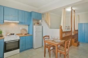 a kitchen with blue cabinets and a table with chairs at Kalimera Karpathos Exclusive Villas in Afiartis