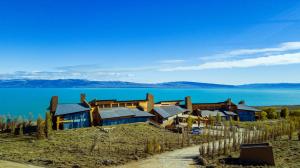 a house on a hill next to the water at Design Suites Calafate in El Calafate