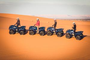 Eine Gruppe von Menschen auf atvs in der Wüste in der Unterkunft Azawad Luxury Desert Camp in Merzouga