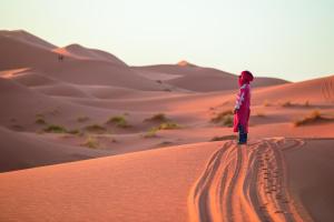 a person standing on a sand dune in the desert at Azawad Luxury Desert Camp in Merzouga