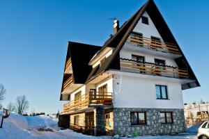 una casa con techo negro en la nieve en Pokoje "u Kuruców" en Bukowina Tatrzańska