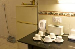 a kitchen with a counter with cups and a toaster at Eleven Bed & Breakfast in New Delhi