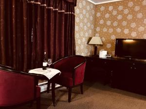 a room with a table with a wine glass and a television at Alpine Inn & Suites in Revelstoke
