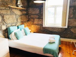 Bett in einem Zimmer mit einer Steinmauer in der Unterkunft D'ouro in Porto