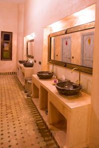 a bathroom with three sinks and a row of mirrors at Riad Azawad in Merzouga