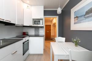 a kitchen with white cabinets and a white table at Piriko Studio Apartments in Rovaniemi