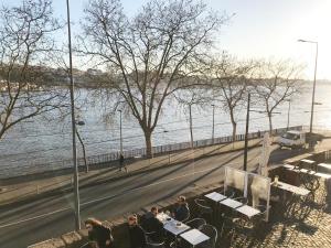 a group of people sitting at tables by the water at D'ouro in Porto