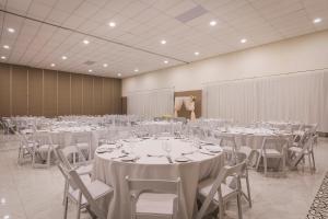 un salón de banquetes con mesas y sillas blancas en Ocean el Faro Resort - All Inclusive en Punta Cana