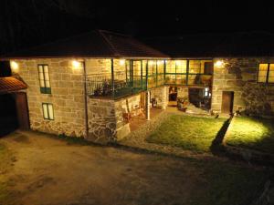 una casa de piedra por la noche con luces encendidas en Casa Rural Rectoral de Candás, en Rairiz de Veiga