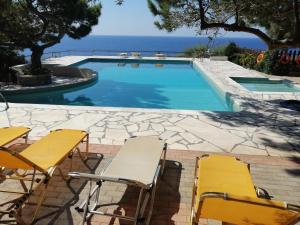 basen z żółtymi krzesłami i oceanem w obiekcie Ferma Solaris Apartments w mieście Agia Fotia