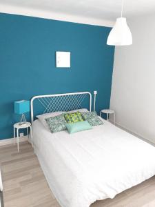 una camera con un letto bianco e una parete blu di Aux Alyscamps a Arles