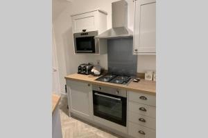 uma cozinha com armários brancos e um forno com placa de fogão em Two Hoots em Leeds