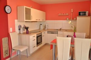 a kitchen with red walls and a table and chairs at Ferienhaus Müritzsonne / EG-Appartement in Marienfelde