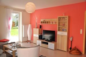 sala de estar con paredes de color naranja y TV de pantalla plana. en Ferienhaus Müritzsonne / EG-Appartement, en Marienfelde