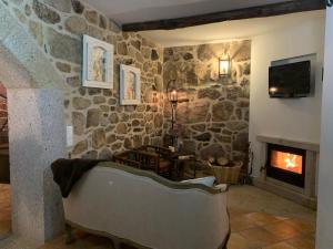 a living room with a stone wall with a fireplace at Casa D'Campo Ferreira in Pitões das Júnias