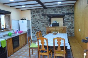 cocina con mesa, sillas y pared de piedra en Casa el Fanoso, en Luarca