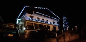 a house with christmas lights on the roof at night at Hôtel Flor'Alpes in La Giettaz
