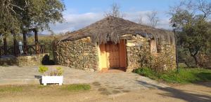 a small stone building with a door and a grass roof at complejo rural el prado in Logrosán