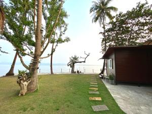 a yard with a house and the ocean in the background at Somphoch Garden in Trat