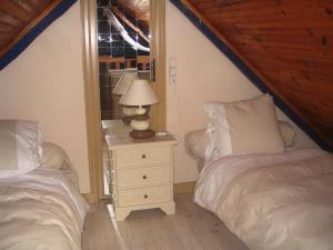 a bedroom with two beds and a lamp on a night stand at A L'Ombre Du Figuier in Saint-Thois