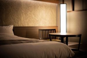 a bed in a room with a lamp on top of it at Yunokawa Prince Hotel Nagisatei in Hakodate