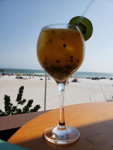 a glass of wine sitting on a table near the beach at Le Bon Vivant 108 in Arraial do Cabo