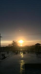 a sunset over a parking lot with the sun setting at Le Bon Vivant 108 in Arraial do Cabo